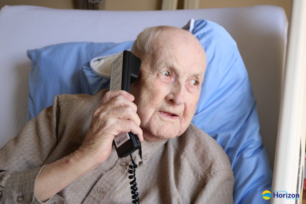 Photo d'un patient avec des visiteurs venant à la fenêtre de son lit d'hôpital
