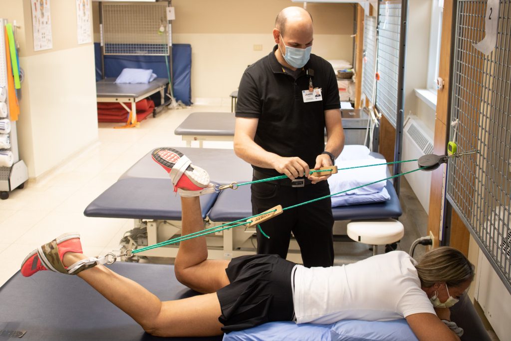 Le physiothérapeute Justin Saulnier rajuste les poulies durant les exercices d'amplitude de mouvement de Carla Chadwick.